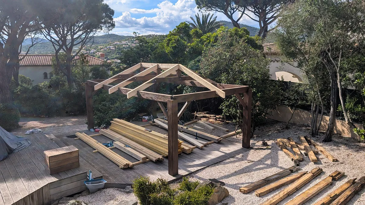 Charpente de la pergola en cours de montage, avec les matériaux au sol